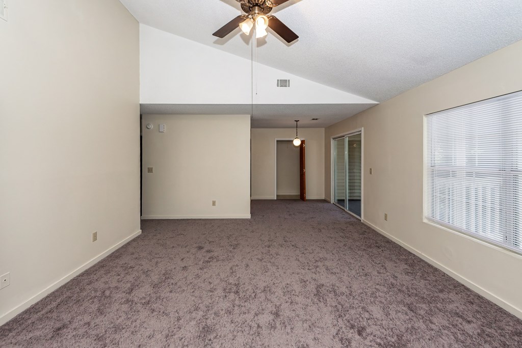 A room with a ceiling fan and carpeted floor.