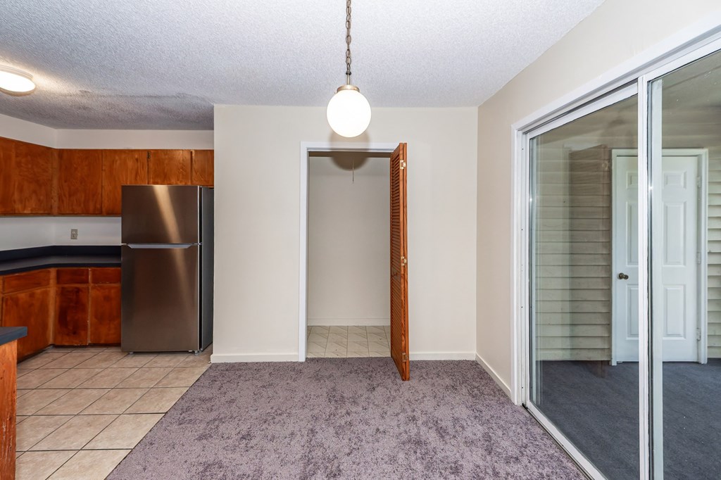A kitchen with a refrigerator and a purple rug.