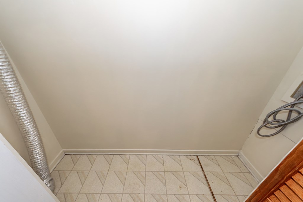 A white bathroom with a tiled floor and a white wall.