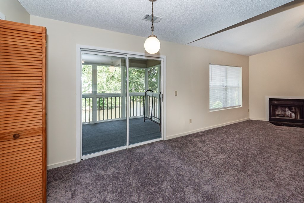 A room with a purple carpet and a sliding glass door leading to a balcony.