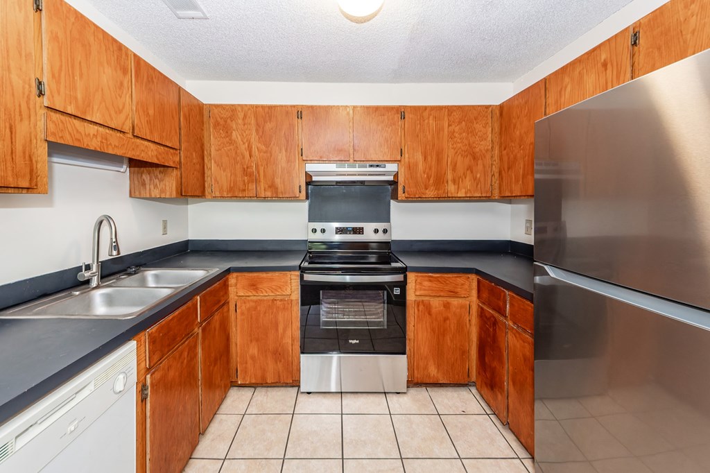 A kitchen with wooden cabinets and a stainless steel refrigerator.
