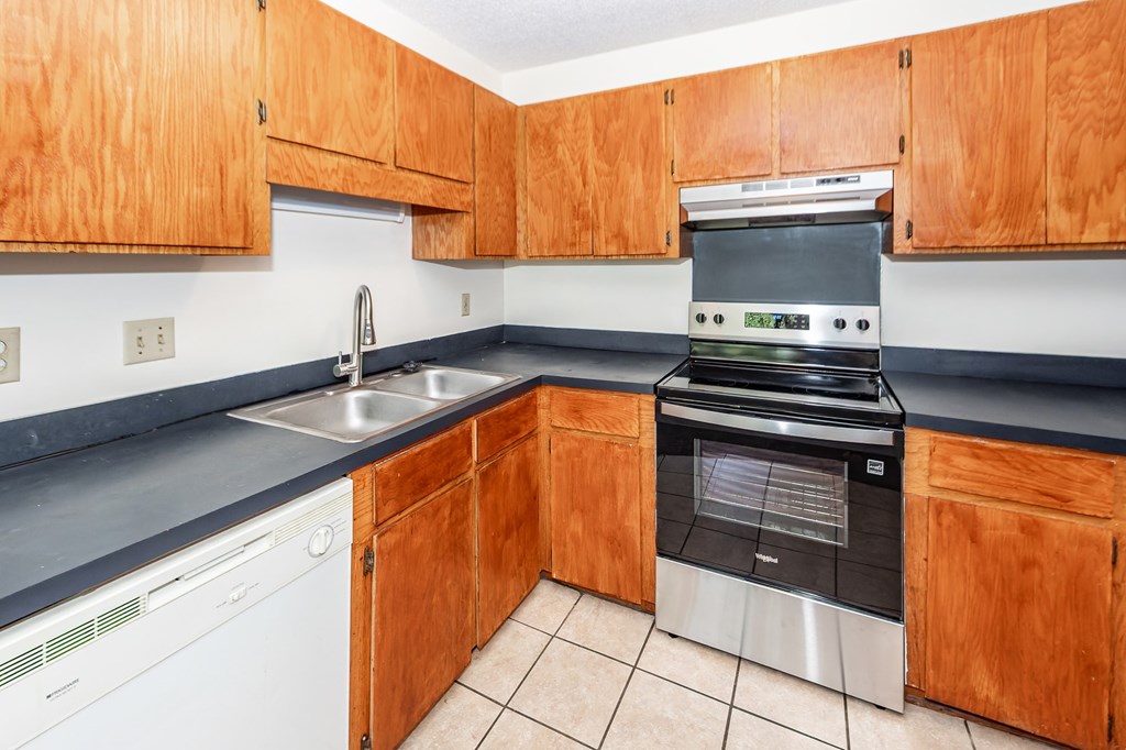A kitchen with wooden cabinets and a stainless steel dishwasher.