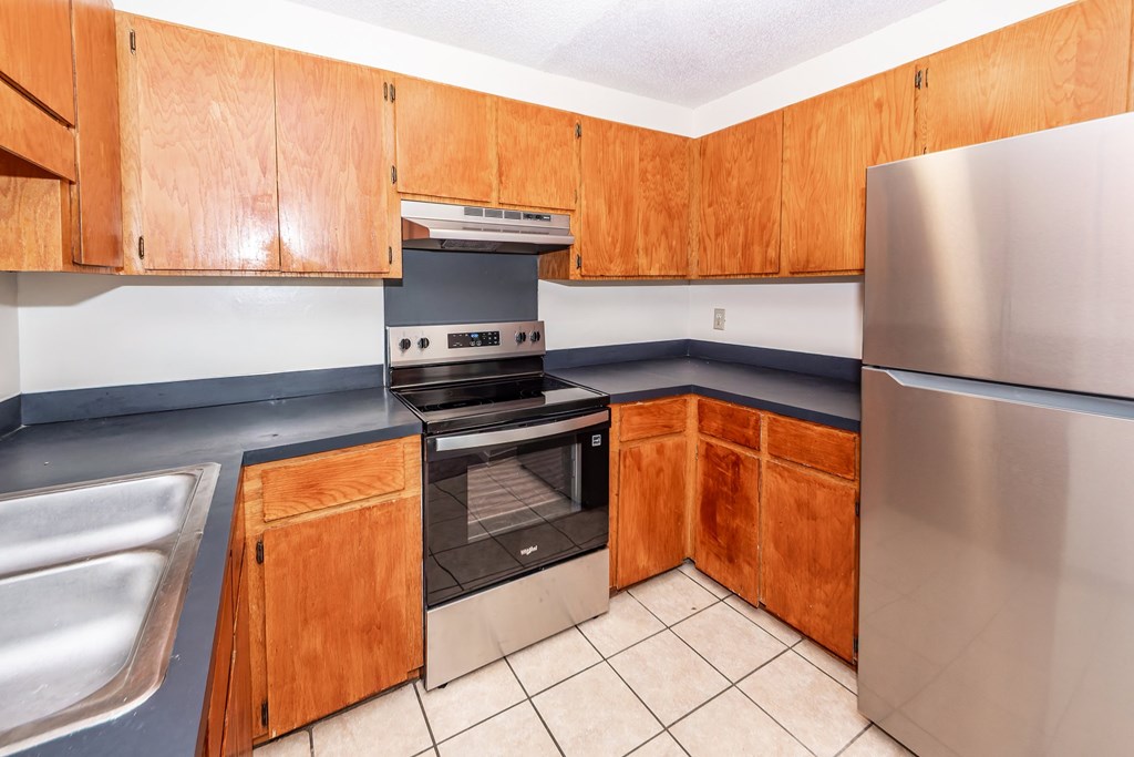 A kitchen with wooden cabinets and a stainless steel refrigerator.