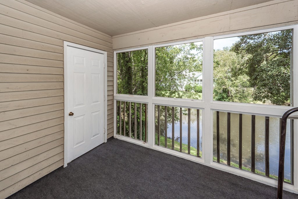 A room with a white door and a balcony with a railing.