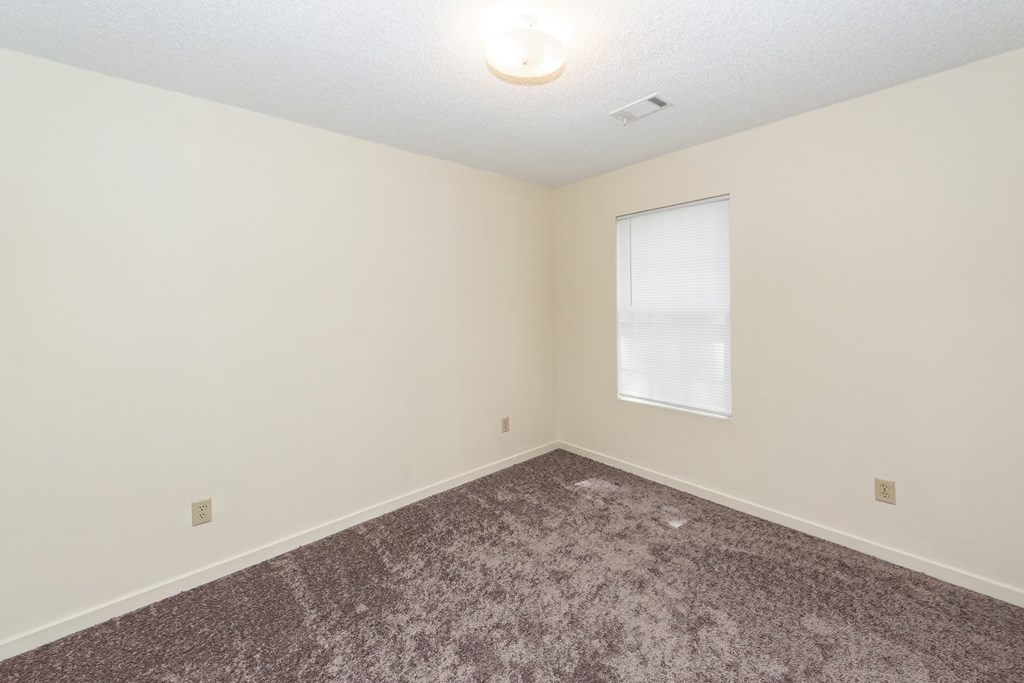 A room with a carpeted floor and a window.