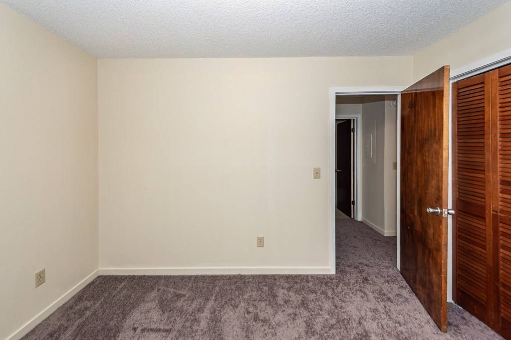 A room with a carpeted floor and a wooden door.