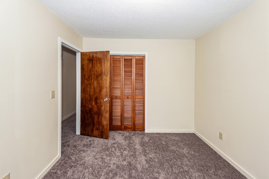 A room with a carpeted floor and a wooden door.