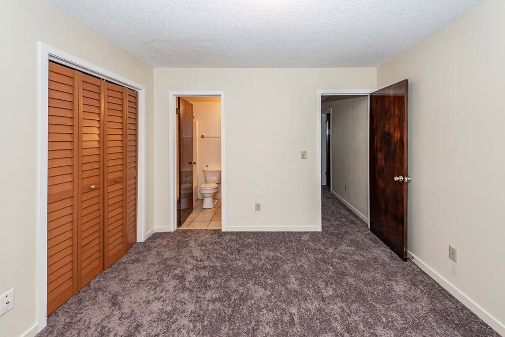A room with a carpeted floor and a toilet in the bathroom.