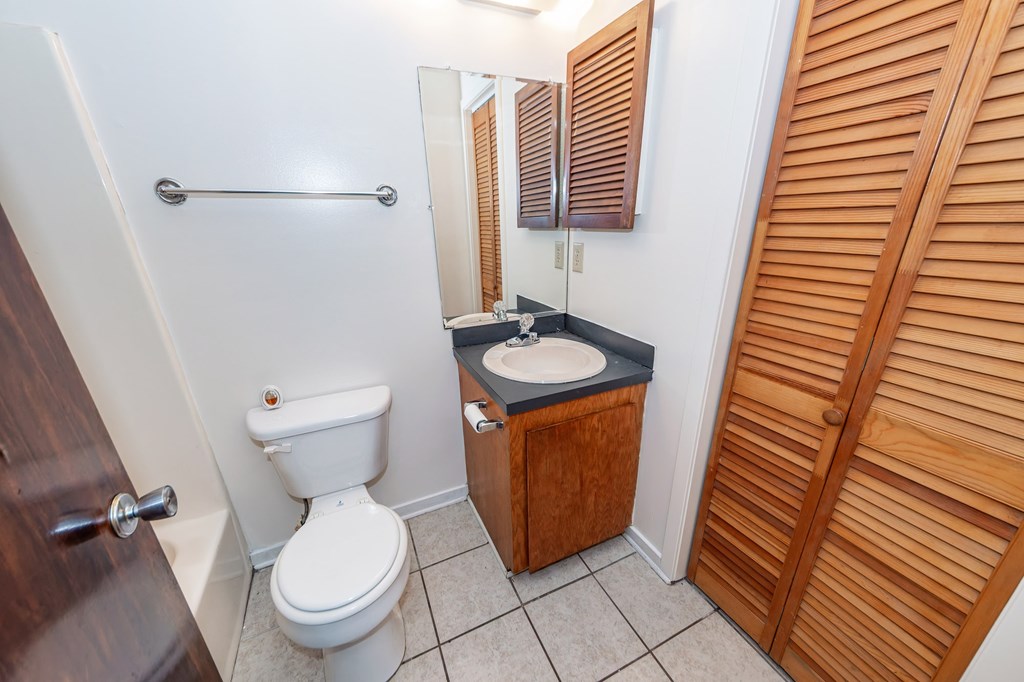 A white toilet sits in a small bathroom next to a sink.