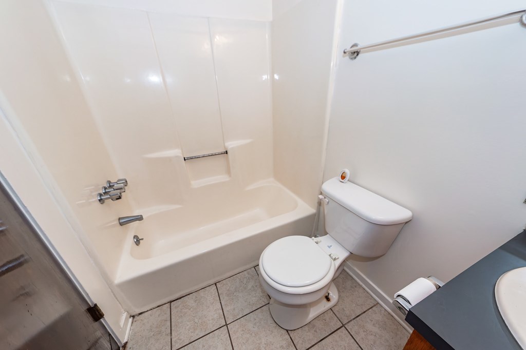 A white toilet sits next to a bathtub in a bathroom.