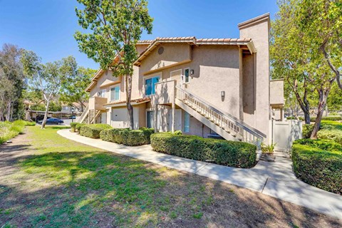 A beige stucco house with a green lawn in front.