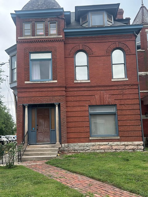 A red brick house with a black door and a small porch.