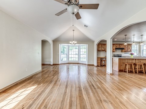 A spacious room with wooden floors and a ceiling fan.