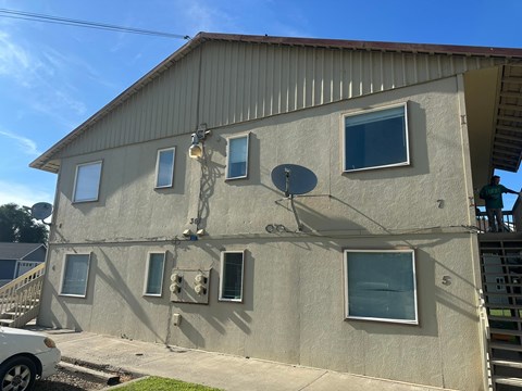 A grey house with a white car parked in front.