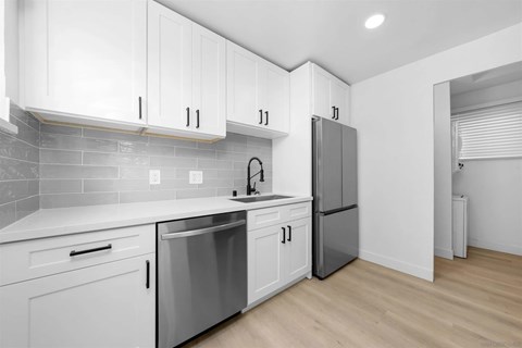 A kitchen with white cabinets and a grey refrigerator.