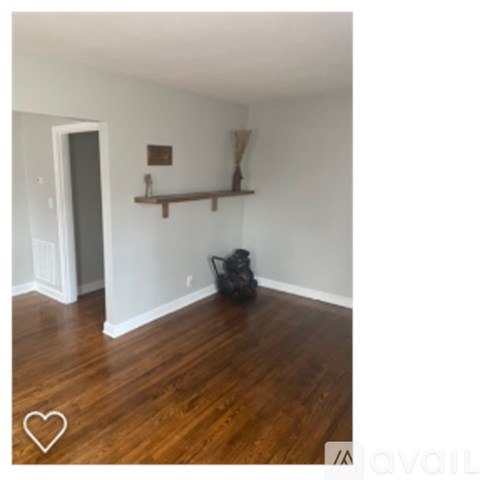A room with wooden floors and a shelf with a few items on it.