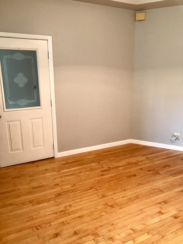 A room with a white door and wooden flooring.