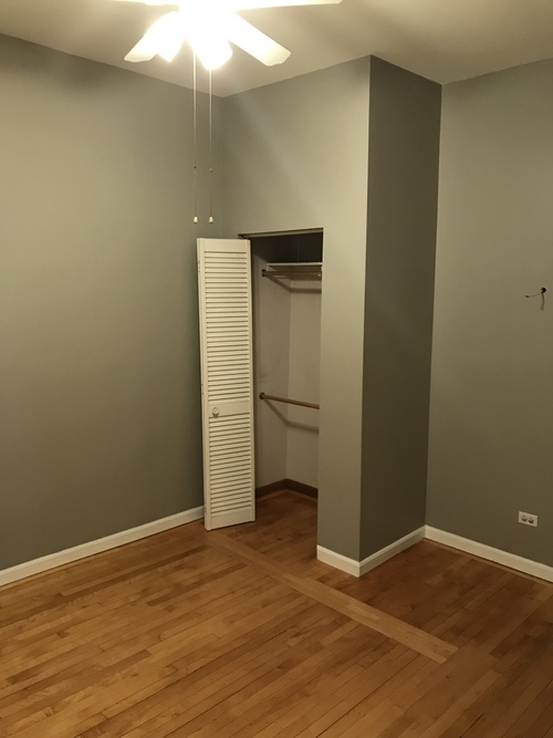 A room with a white ceiling fan and a white closet with a door open.