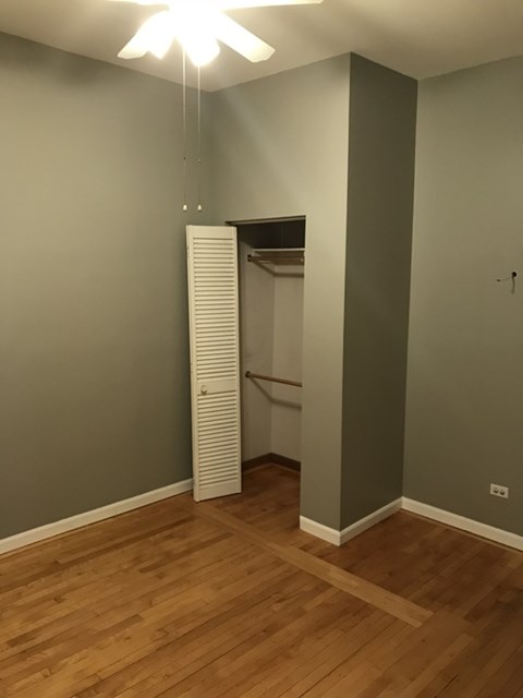 A room with a white ceiling fan and a white closet with a door open.