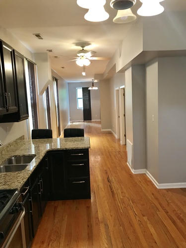 A kitchen with black cabinets and a wooden floor.