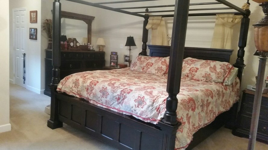 A bed with a floral patterned bedspread sits in a room with a wooden headboard.