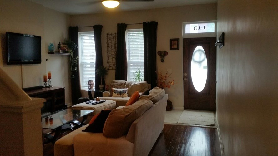 A living room with a couch, television, and a door.