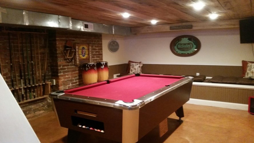 A pool table in a room with a brick wall and a fireplace.