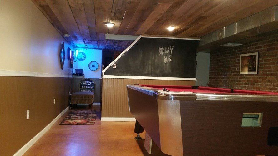 A pool table in a room with a chalkboard on the wall.