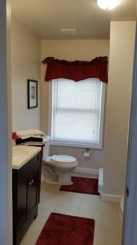 A bathroom with a toilet, sink, and window.