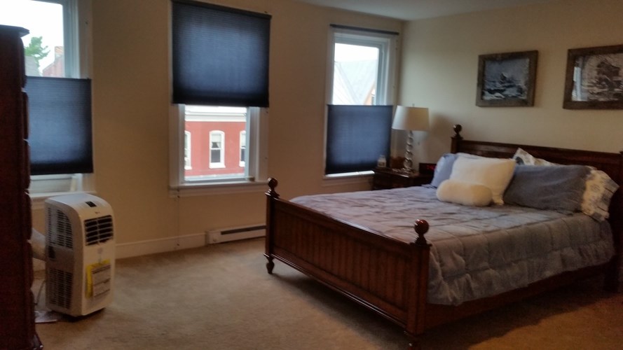 A bedroom with a bed, window, and air conditioner.