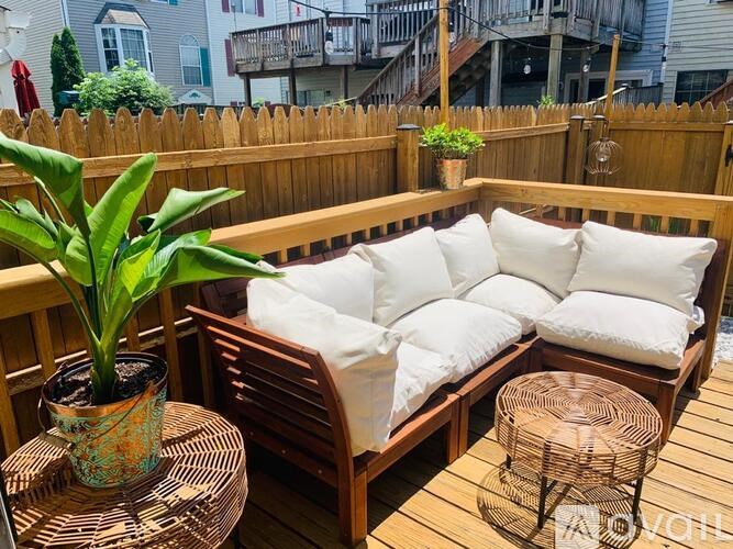 A wooden patio with a couch, table, and potted plant.