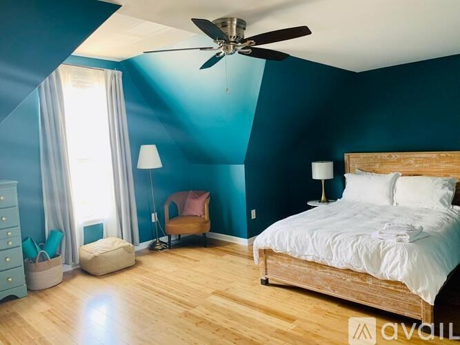 A bedroom with a bed, chair, and window.