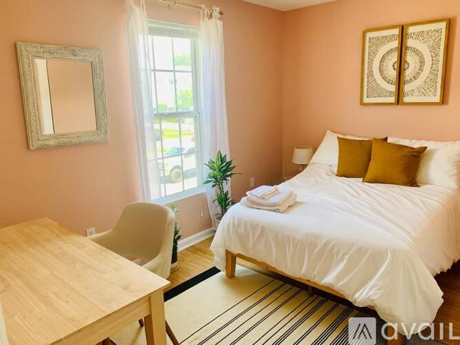 A bedroom with a bed, a chair, a table, and a mirror on the wall.