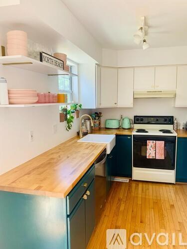 A kitchen with a wooden counter top and a stove with a pot on it.
