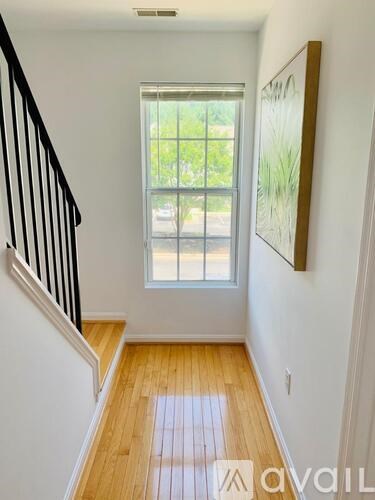 A hallway with wooden floors and a staircase leading to a window.