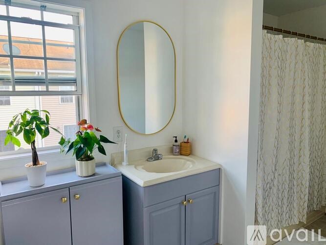 A bathroom with a sink, mirror, and two potted plants.