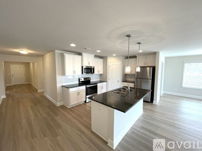 A modern kitchen with white cabinets and a black countertop.