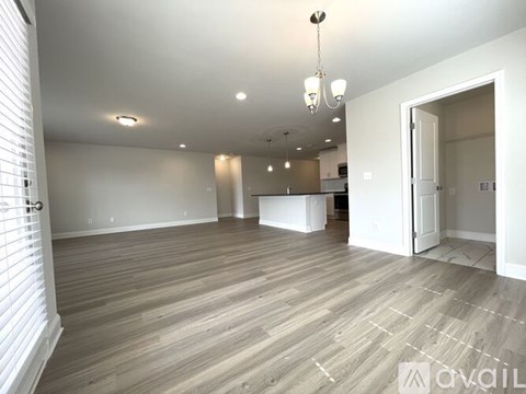 A spacious room with wooden flooring and a chandelier.