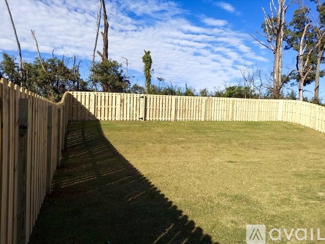 A backyard with a wooden fence and a grassy area.