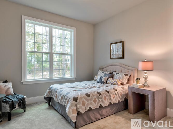 A bedroom with a bed, nightstand, and window.
