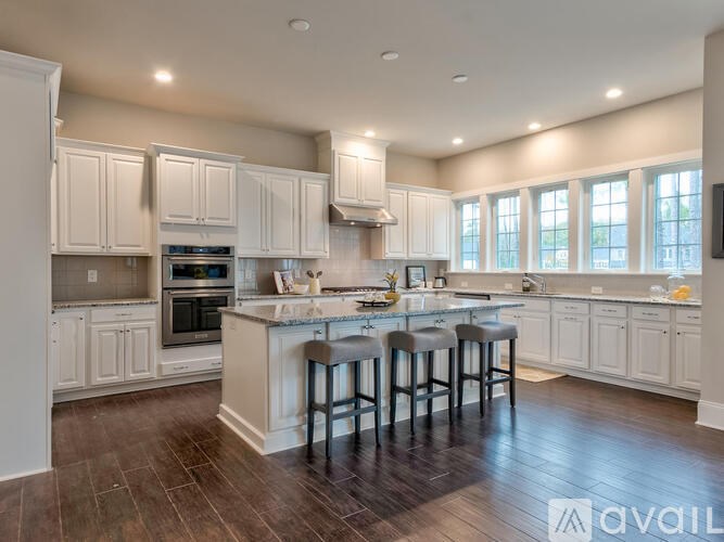 A kitchen with white cabinets and a central island with three stools.