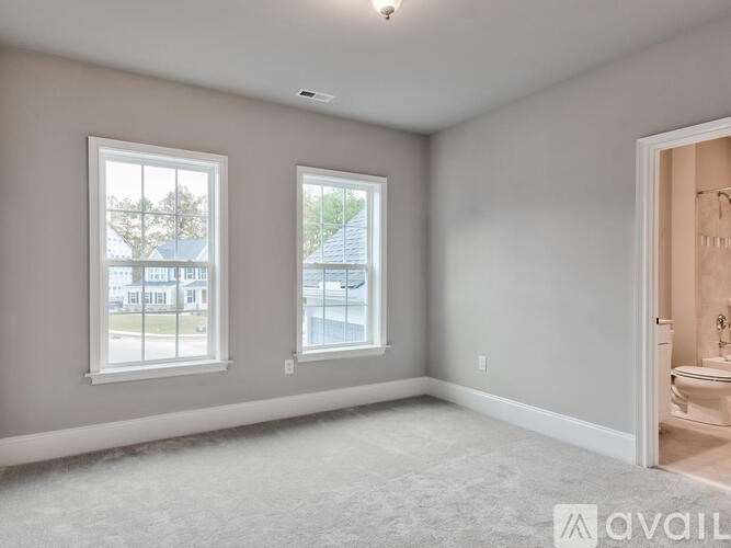 A spacious room with two windows and a bathroom visible through the open door.