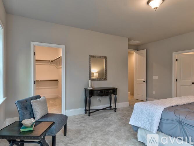 A bedroom with a bed, a chair, and a desk.