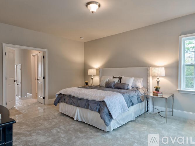 A bedroom with a large bed and two lamps.