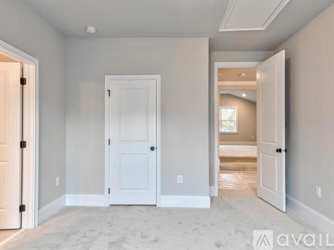 A room with a white door and a carpeted floor.