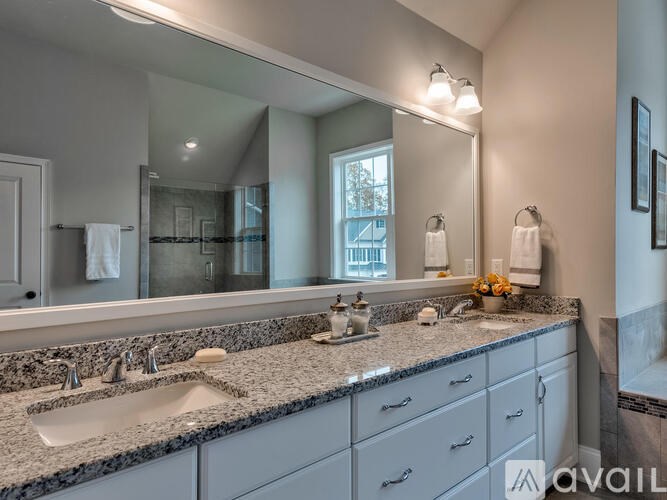 A bathroom with a large mirror above a sink with a granite countertop.