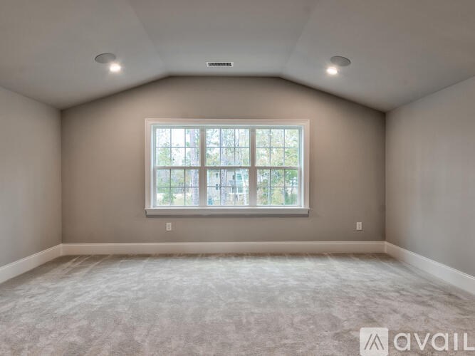 A spacious room with a large window and carpeted floor.