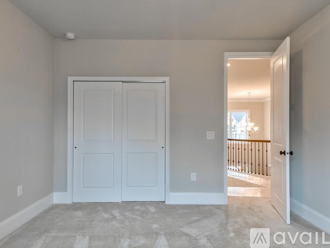 A room with a white door and a carpeted floor.