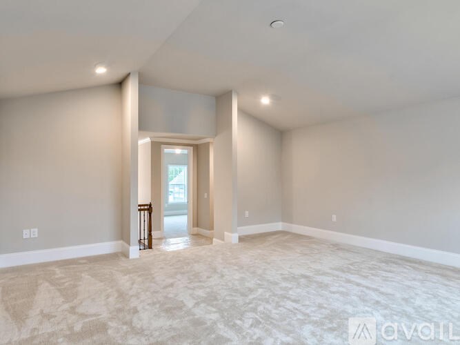 A spacious room with a carpeted floor and a doorway leading to another room.