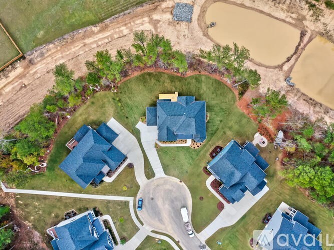 A bird's eye view of a residential area with houses and a pond.